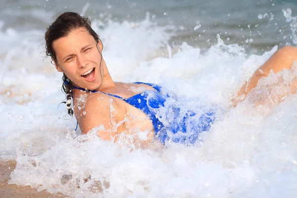 Photo a young woman  lying on the beach sea, among waves and foa — Stock Photo, Image