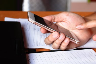 Çalışırken akıllı telefon, dizüstü bilgisayar kullanarak genç adam el yakın çekim 