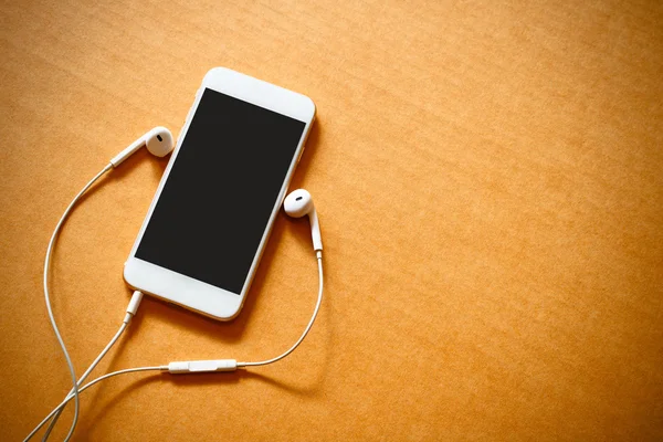 Smartphone com tela em branco e fones de ouvido em fundo de madeira — Fotografia de Stock