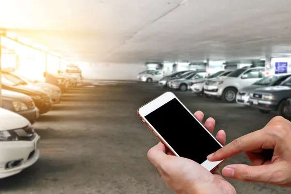 Inteligentny telefon pokazuje pusty ekran w dłoni człowieka z rozmycie parku samochodów — Zdjęcie stockowe