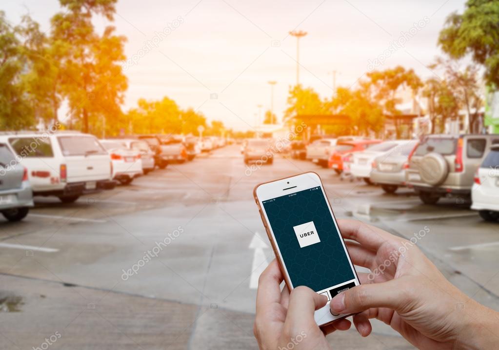 CHIANG MAI,THAILAND-JUNE 25,2016 :Man hands holding iPhone 6 showing Uber app on screen. Blurred street view with car, Uber is app-based transportation network.