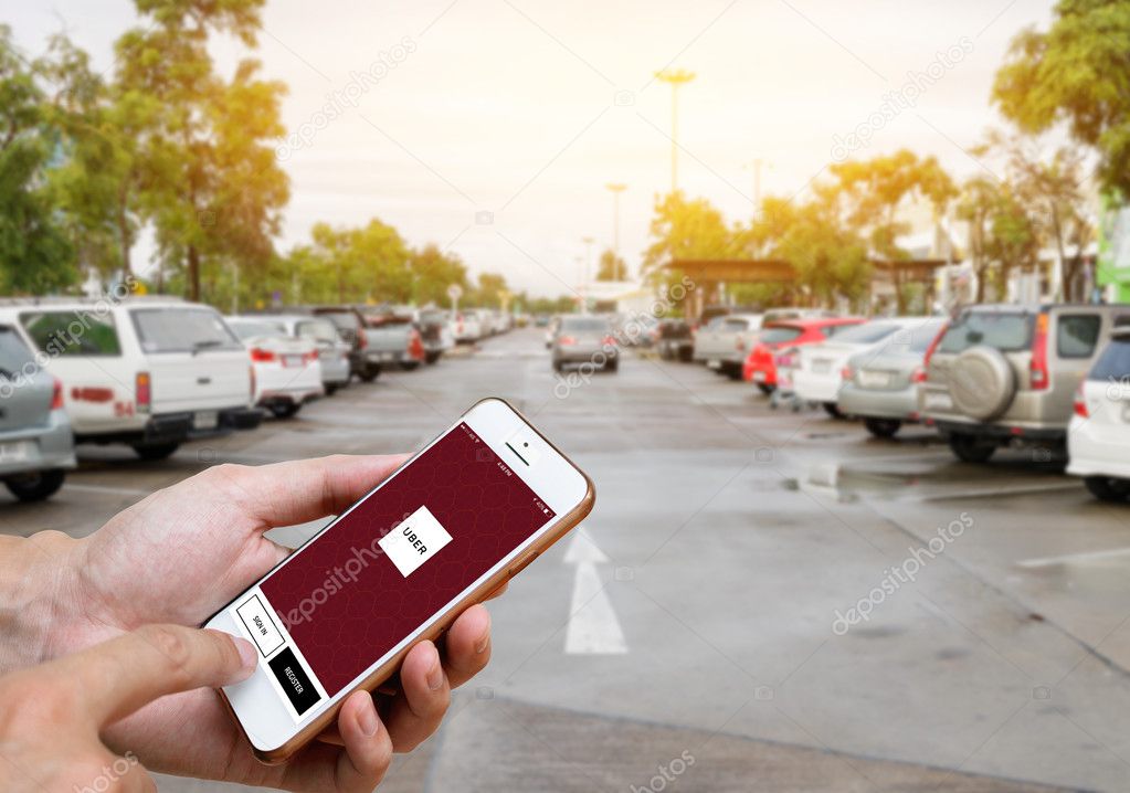 CHIANG MAI,THAILAND-JUNE 25,2016 :Man hands holding iPhone 6 showing Uber app on screen. Blurred street view with car, Uber is app-based transportation network.