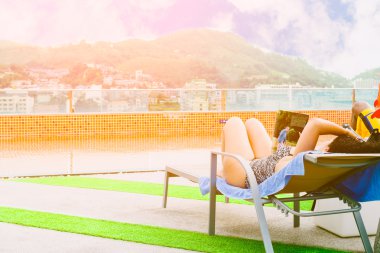 Kadın yatakta, onun okuma kitabı-Yüzme Havuzu, rahatlatıcı en iyi otelde güneşlenme.