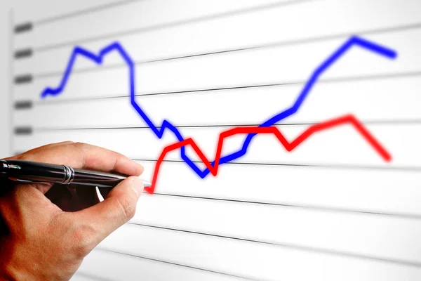 Fechar a mão segurando caneta desenhando um gráfico de negócios no laptop — Fotografia de Stock