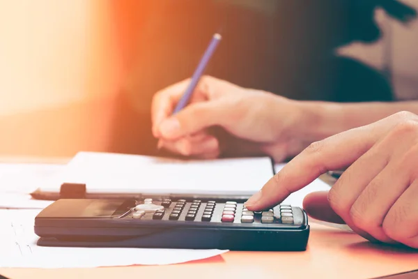 Acercamiento mujer joven con calculadora contando haciendo notas en ho — Foto de Stock