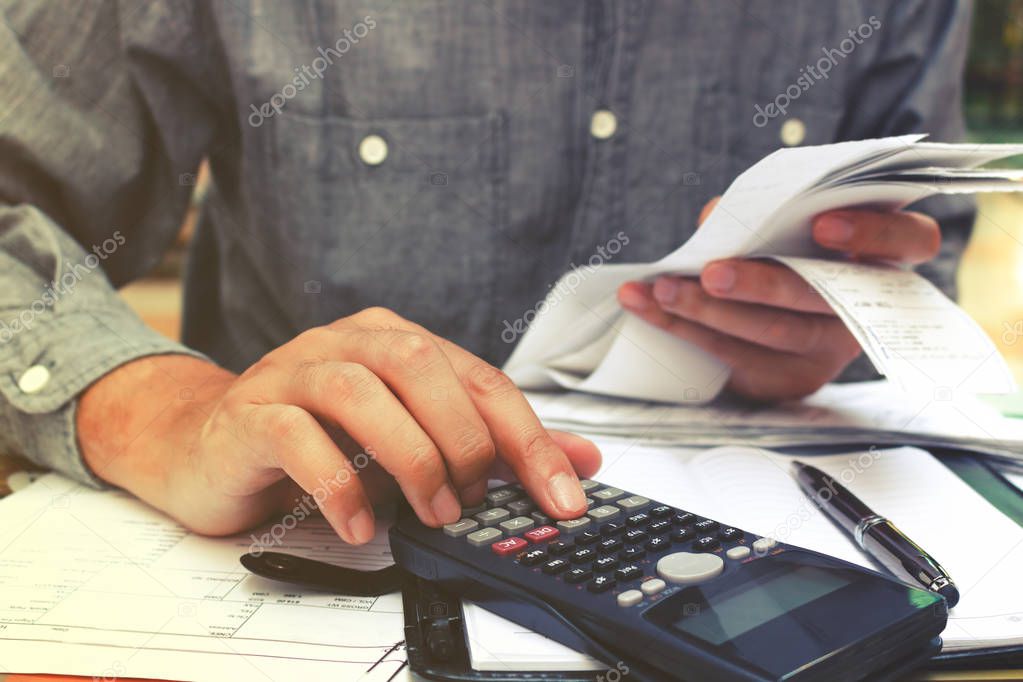 Man using calculator and calculating bills in home office.