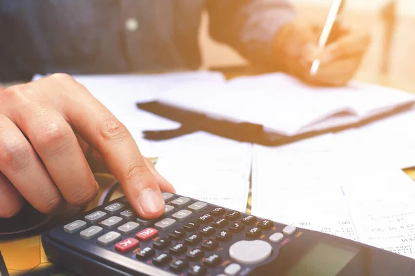 Feche o homem de mão usando calculadora e anote no escritório em casa . — Fotografia de Stock