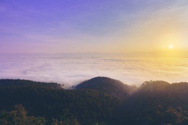 Görünümü bilgi puslu Vadisi ile kayalık dağın zirvesinde gündoğumu.