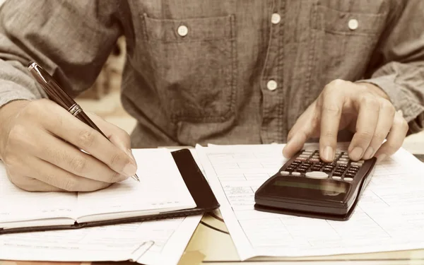 Fiatal férfi számológép és írásban jegyzet otthon. — Stock Fotó