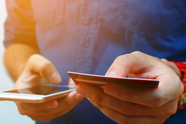 Primer plano de hombre joven utilizar el teléfono inteligente y la celebración de la tarjeta de crédito, s —  Fotos de Stock