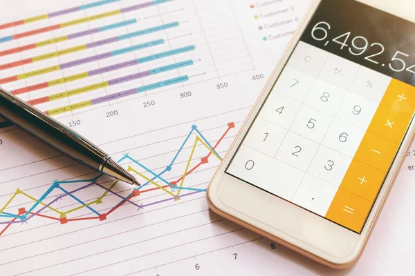 Data analyzing with calculator mobile phone and pen. from charts