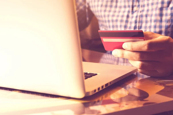 Homem usando laptop e segurando cartão de crédito com compras on-line ou conceito de internet banking . — Fotografia de Stock