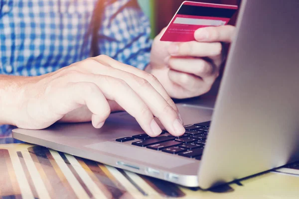 Fechar mão homem digitando teclado laptop e segurando cartão de crédito — Fotografia de Stock