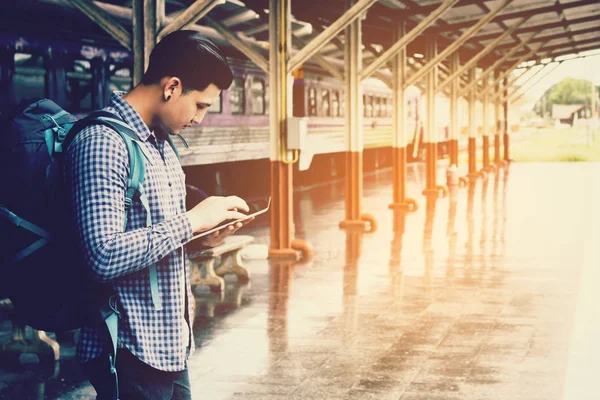Asya adam sırt çantası için seyahat tren istasyonu ve tablet kullanma 