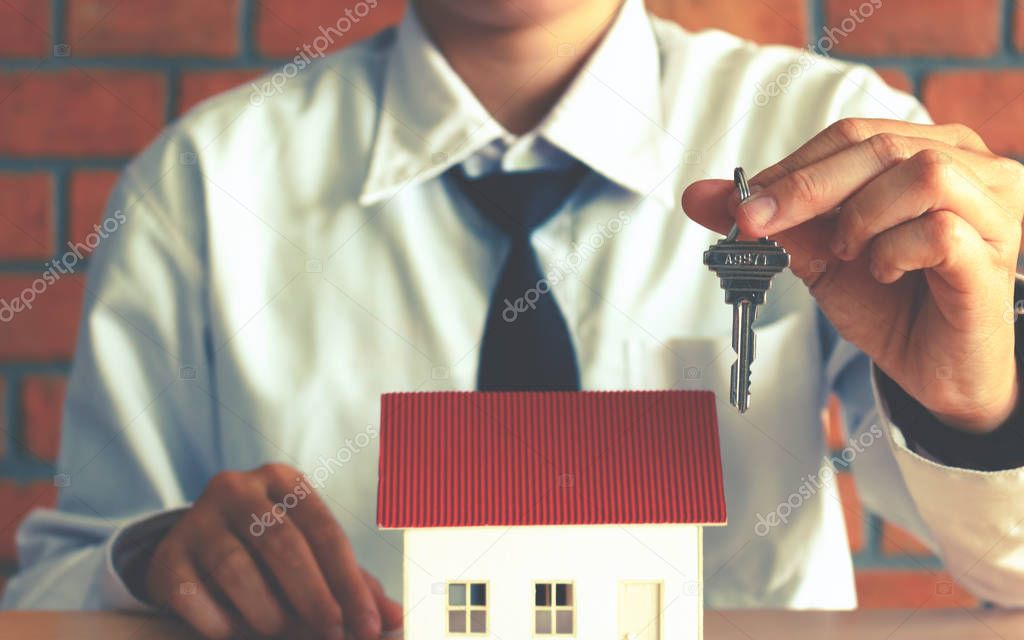Asian salesman holding key and giving for customer with home con
