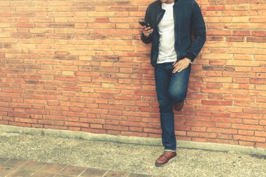 Akıllı adam akıllı telefon duvar arka planda tutan ile ayakta.