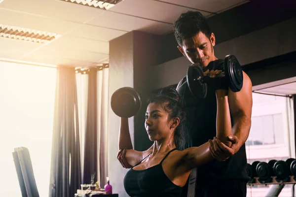 Personal trainer ajudando mulher trabalhando elevador pesados halteres dois — Fotografia de Stock