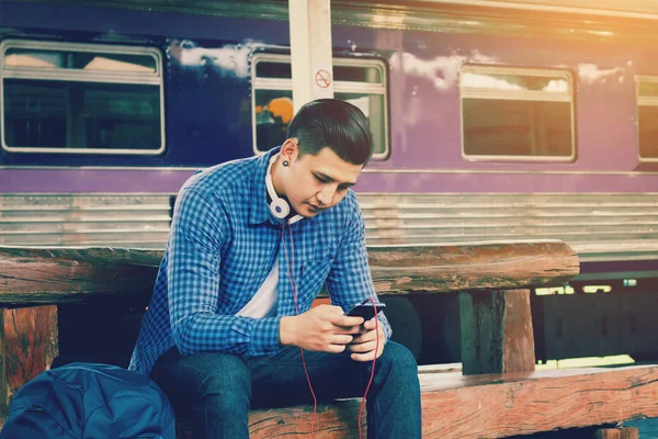 Cep telefonu tutarak ve app şarkı listesini kullanarak akıllı Asyalı adam