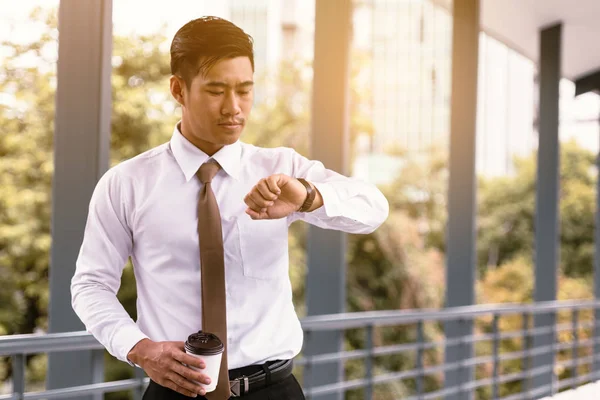 若いアジア男性立ってコーヒー カップ w を押し時間をチェック — ストック写真