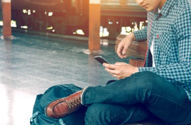 Asya hipster akıllı adam cep telefonu app şarkıyla kullanarak holding