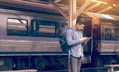Asya adam sırt çantası için seyahat tren istasyonu ve tablet kullanma 