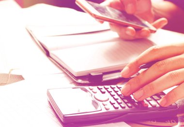 Akıllı telefon görünümlü veri ve masa başında üzerinde hesaplama ho kullanan adam