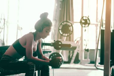 Asyalı kadın spor salonunda oturan club ve rahatlatıcı ile müzik dinlemek bir