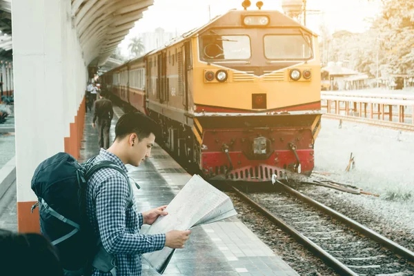 Tren istasyonunda duran ve harita tutarak Asya akıllı genç adam 