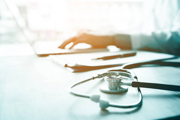 Doctor using laptop at desk in clinic working on computer at roo