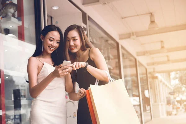 Дві азіатські жінки стоять в магазині спереду з щасливим спостереженням за посмішкою — стокове фото