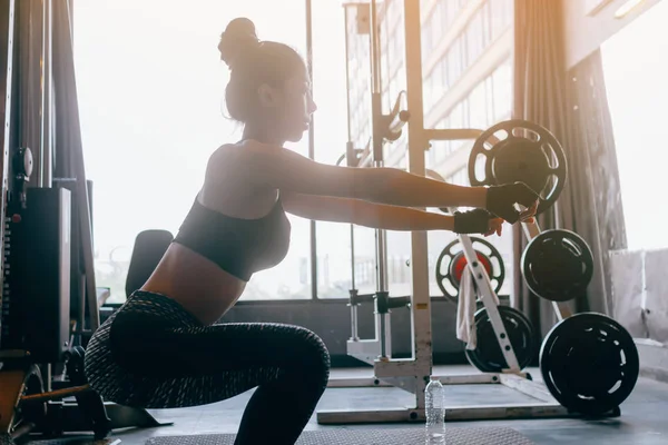 Mladá asijská žena v sportovní dělá squatu na kryté tělocvičně heath. — Stock fotografie