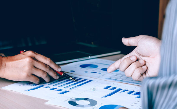 Two businessman pointing on summary report graph and talking abo