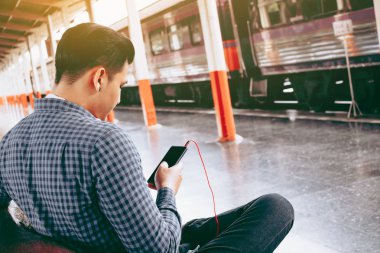 Cep telefonu kullaranarak tutan genç Asyalı hipster adamın arkadan görünüş 