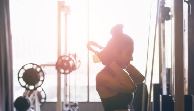 Spor salonunda müzik dinleme için kulaklık giyen Asyalı kadın.