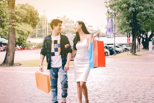 Joven pareja feliz caminando por la calle y sosteniendo bolsas de compras . —  Fotos de Stock