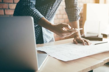 Adam ayakta Smartphone'da yazarak ve modern ofisinde çalışan.