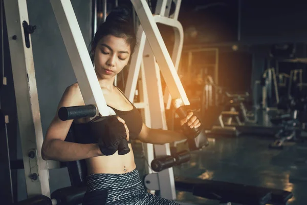 Asian women stronger and pushing weight bar at gym.
