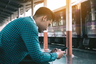 Cep telefonu kullaranarak tutan genç Asyalı hipster adamın arkadan görünüş 
