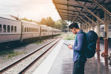 Asya adam sırt çantası için seyahat tren istasyonu ve tablet kullanma 