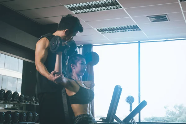 Pessoal homens de treinamento ajudar os braços das mulheres para puxar halteres para — Fotografia de Stock