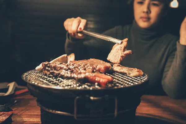 Close up woman cooking pork meat on a charcoal grill in restaura — Stock Photo, Image