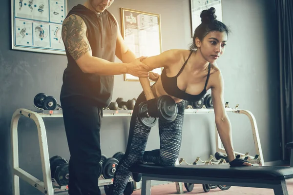 Personal trainer ajudando mulher trabalhando levantar halteres pesados . — Fotografia de Stock