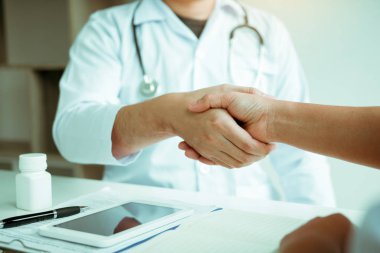 Doktor klinikteki yaşlı hastayla el sıkışıyor..
