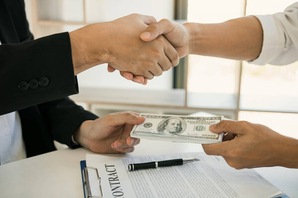 Два корпоративных бизнесмена пожимают друг другу руки, в то время как один человек ставит мон
