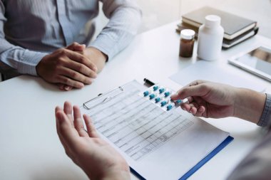 Doktor kullanım hakkında tavsiye vermek için bir ilaç paneli tutuyor. 