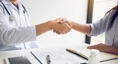 Doktor klinikteki yaşlı hastayla el sıkışıyor..