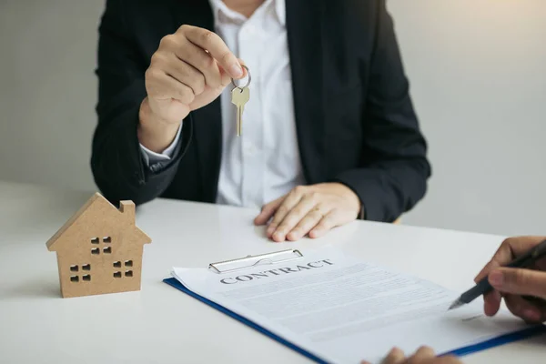 Hand of real estate agent passes the key to new homeowners in of — Stock Photo, Image