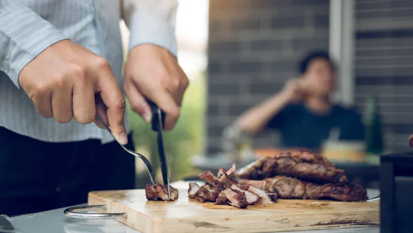 Asiatiska vänner använder en kniv och en gaffel för att skära grillad mig — Stockfoto