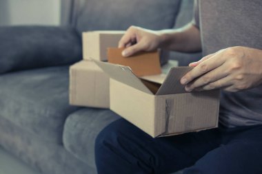 Asyalı girişimci ergen müşterinin sipariş ettiği ürünü kutuya koymak için bir karton kutu açıyor..
