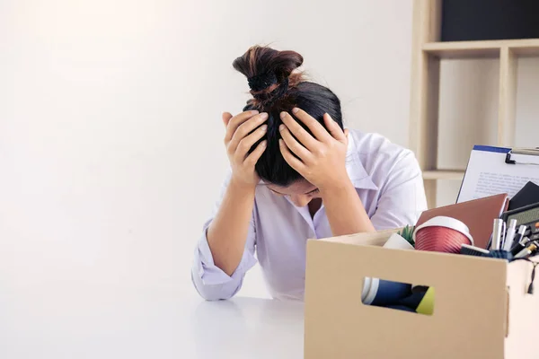 Woman employee used his hand to hold the head feeling sad at his desk when he received the contract envelope for resigning from the company.